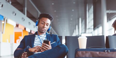 young man in airport in the waiting space listening to music